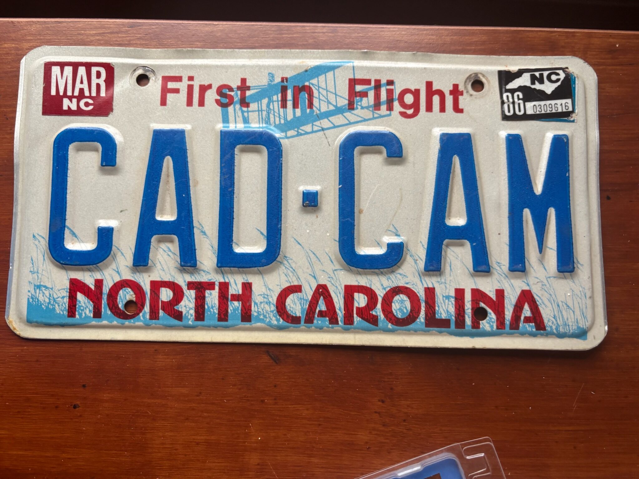 North Carolina license plate reading "CAD-CAM," featuring "First in Flight" text and blue lettering, symbolizing the state's aviation heritage.