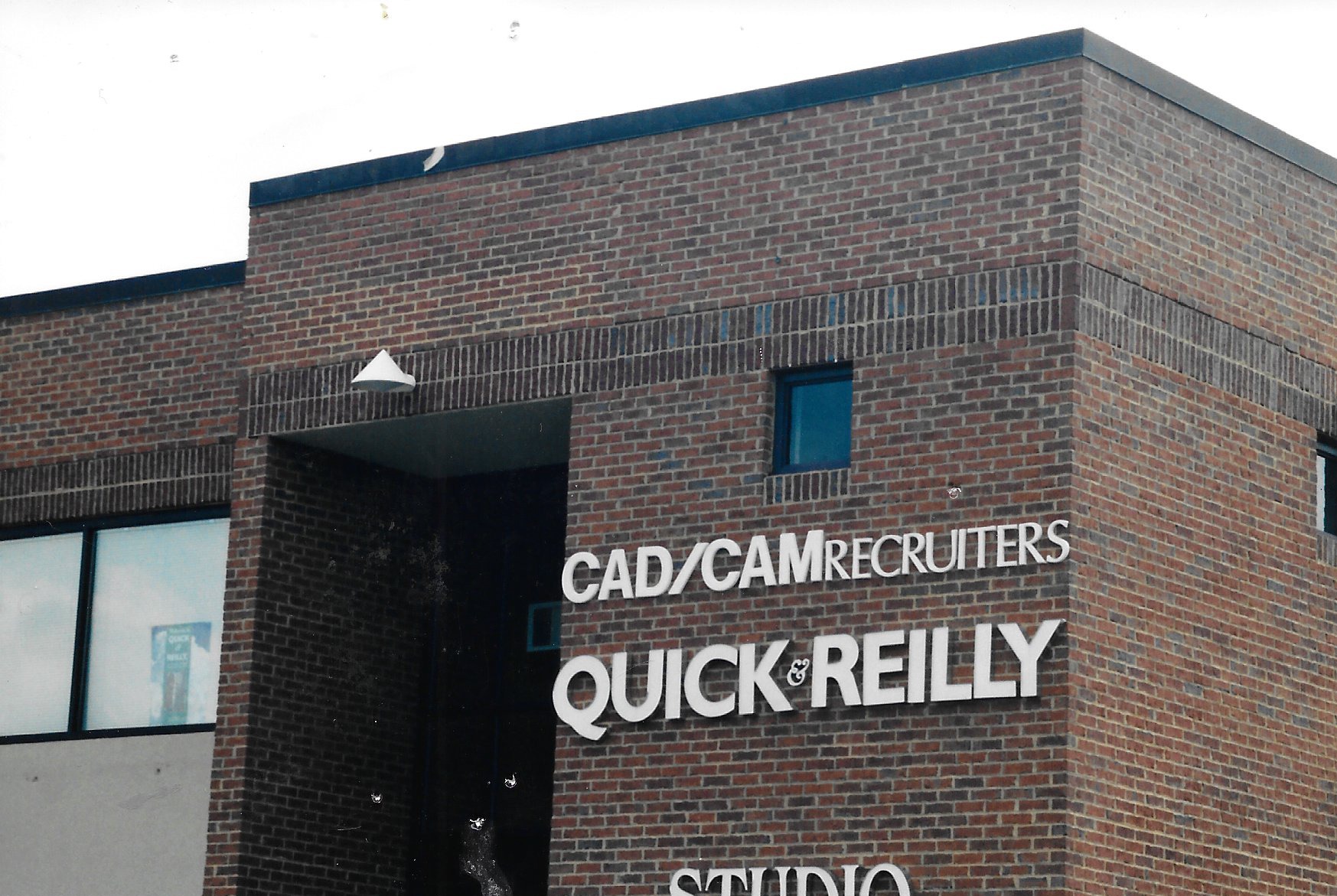 Facade of a brick building featuring signs for "CAD/CAM Recruiters" and "Quick & Reilly," indicating services related to design and recruitment.